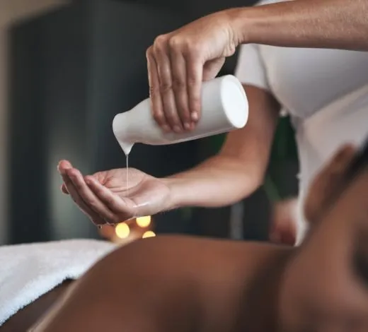 Frau gießt sich Öl in die hand für eine Massage.