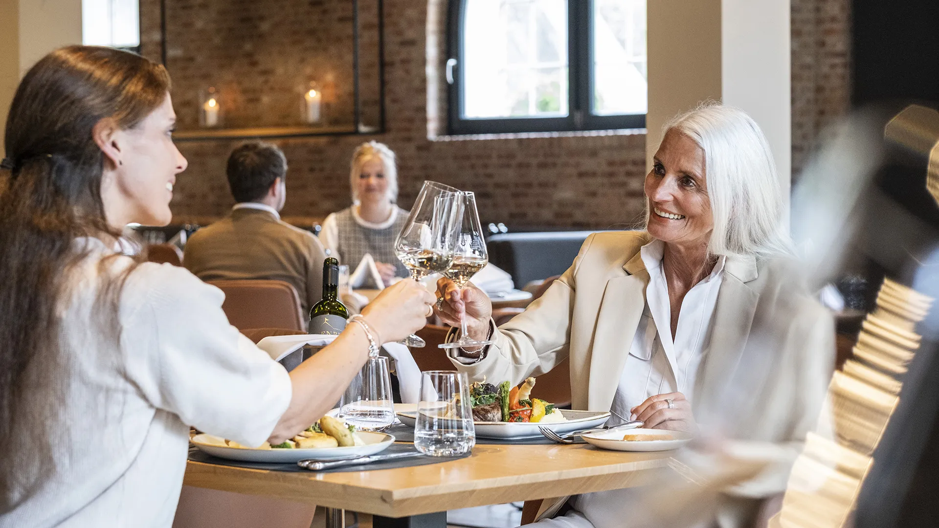 zwei Frauen prosten sich beim Essen zu